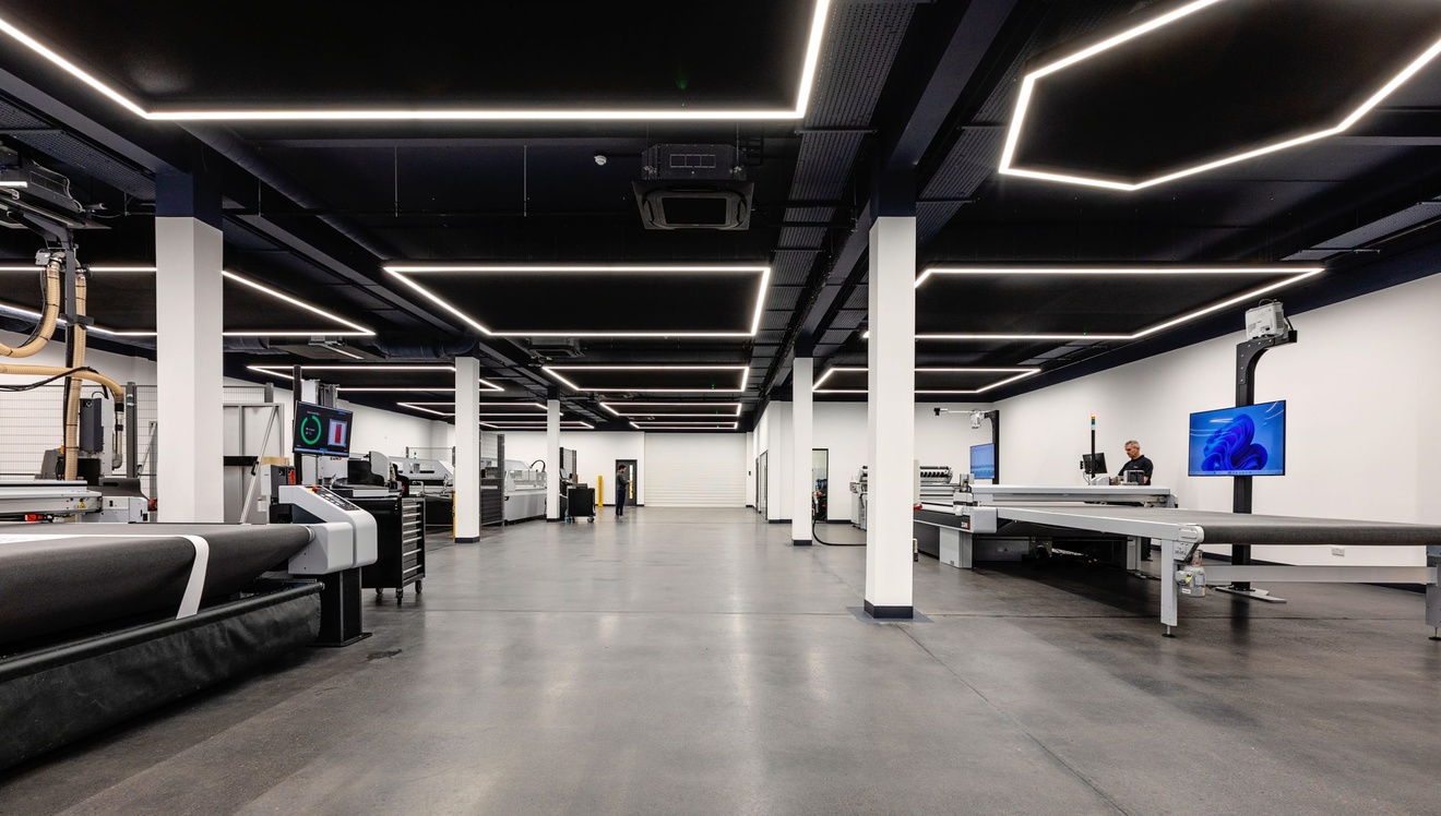 white and black modern work space with machinery to the left and right with white lights and support columns