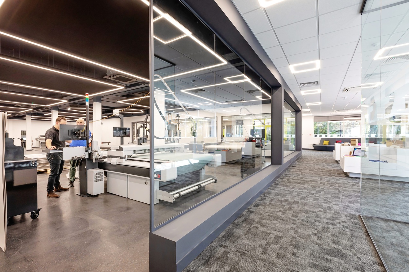 office sitting area with example products to the right with glass wall separating machining area to the left