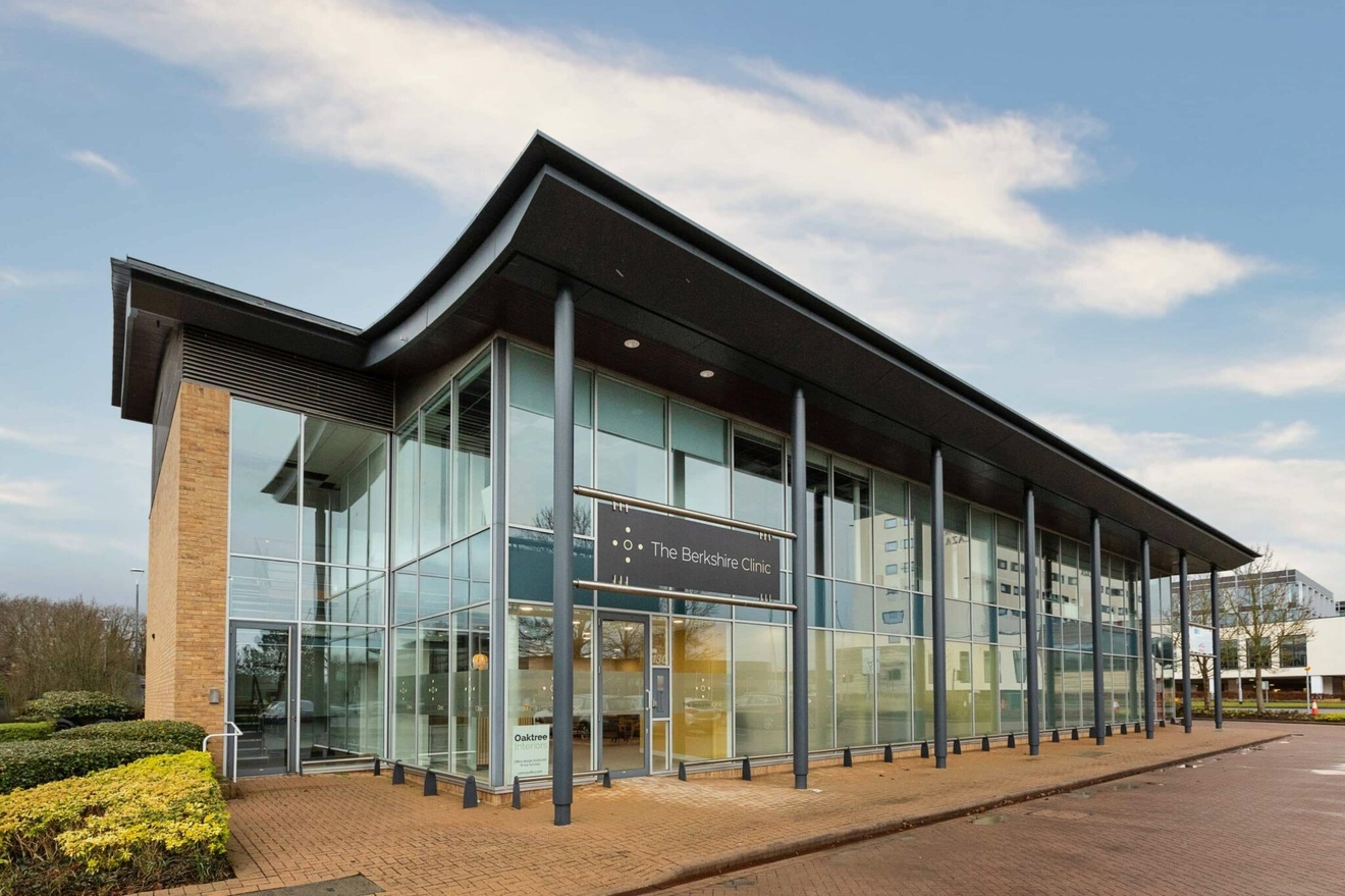 The outside of a building with glass windows spanning across the whole property and support beams across the front side of the building.