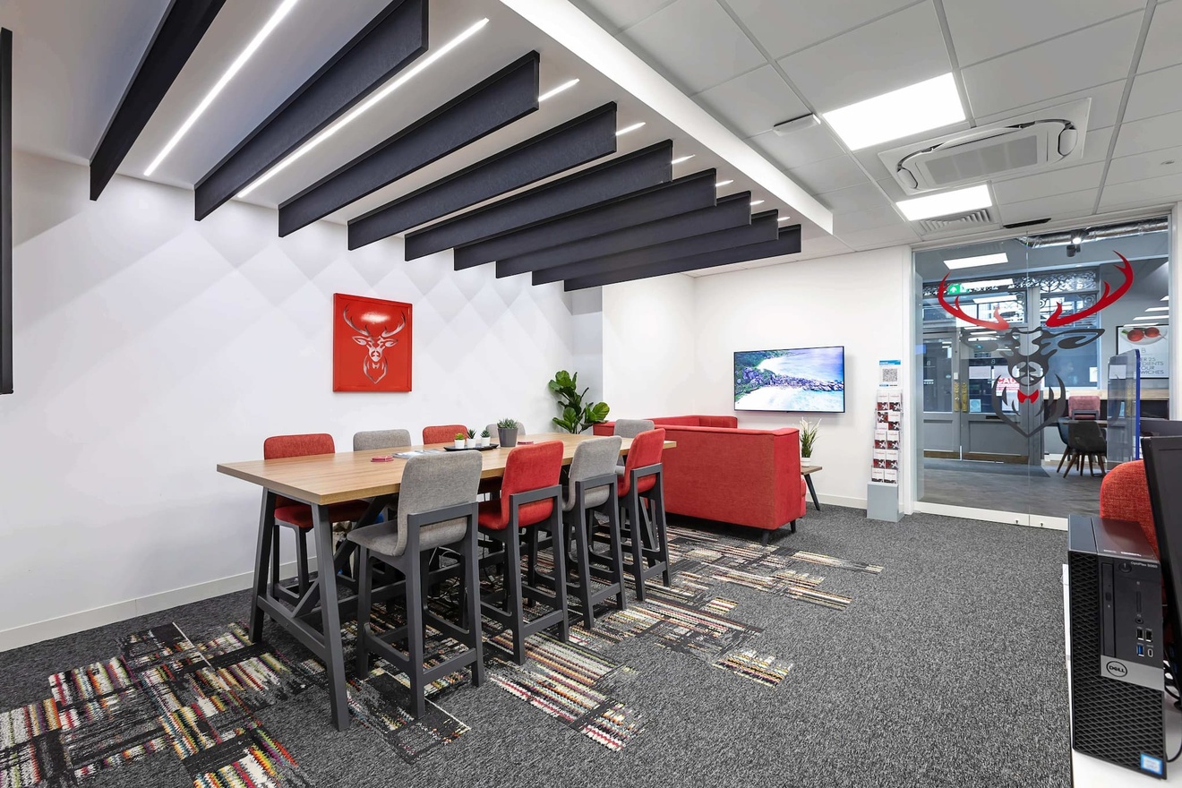 Breakout seating areas in an office, including a table and stools and a sofa area.